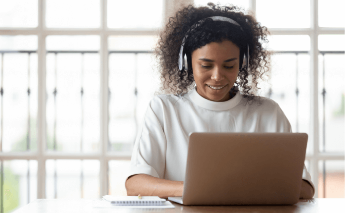 A woman wearing headphones working on some work for her online Master of Computer Science class on the computer.