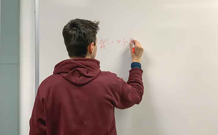 A male student on the whiteboard solve a problem for online Master of Computer Science class.