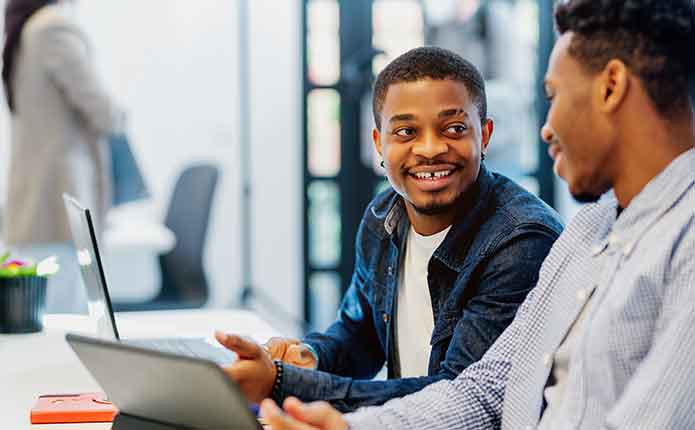 Two male students on the computer working on a solution for a problem for there online Master of Computer Science class.