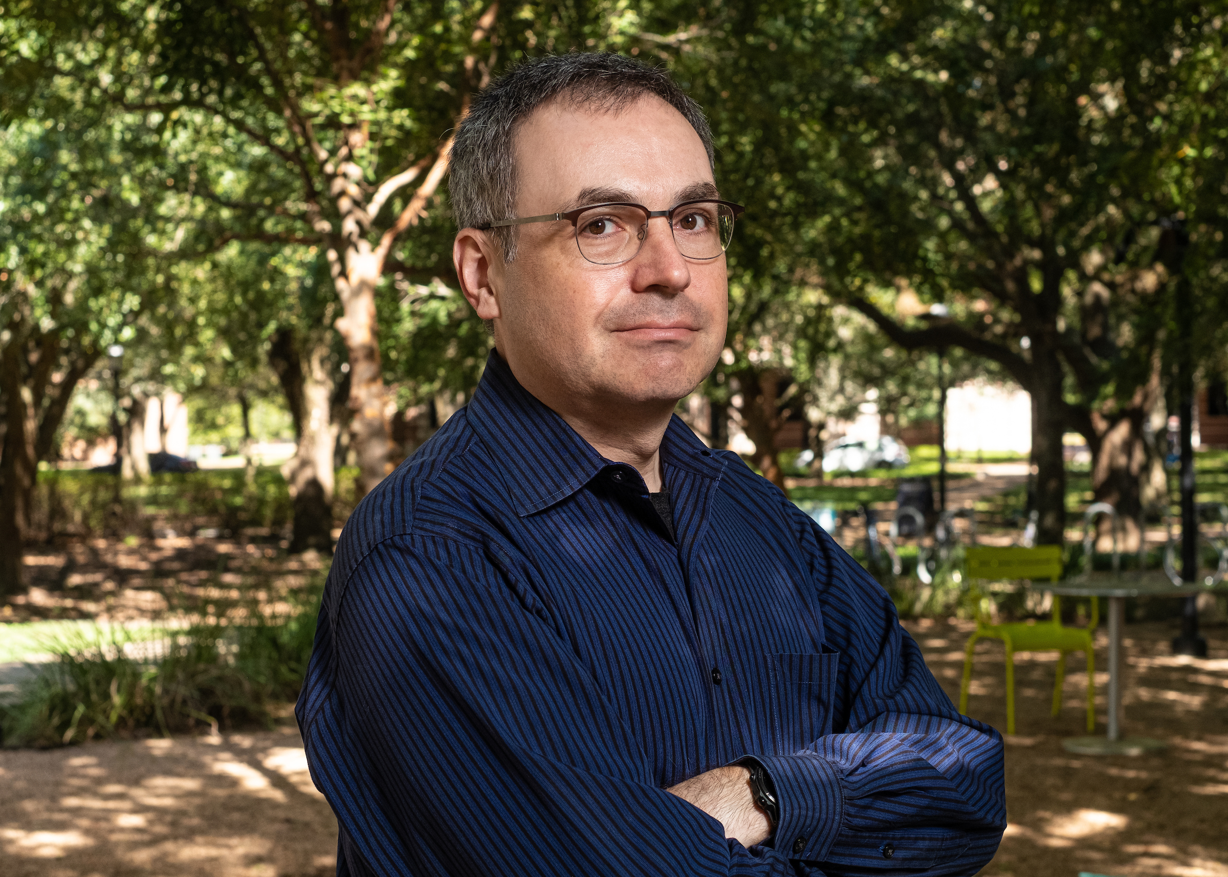 Dan Wallach standing outside by trees on Rice University campus