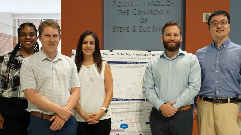 Chevron Digital Scholars stand next to research poster presentation